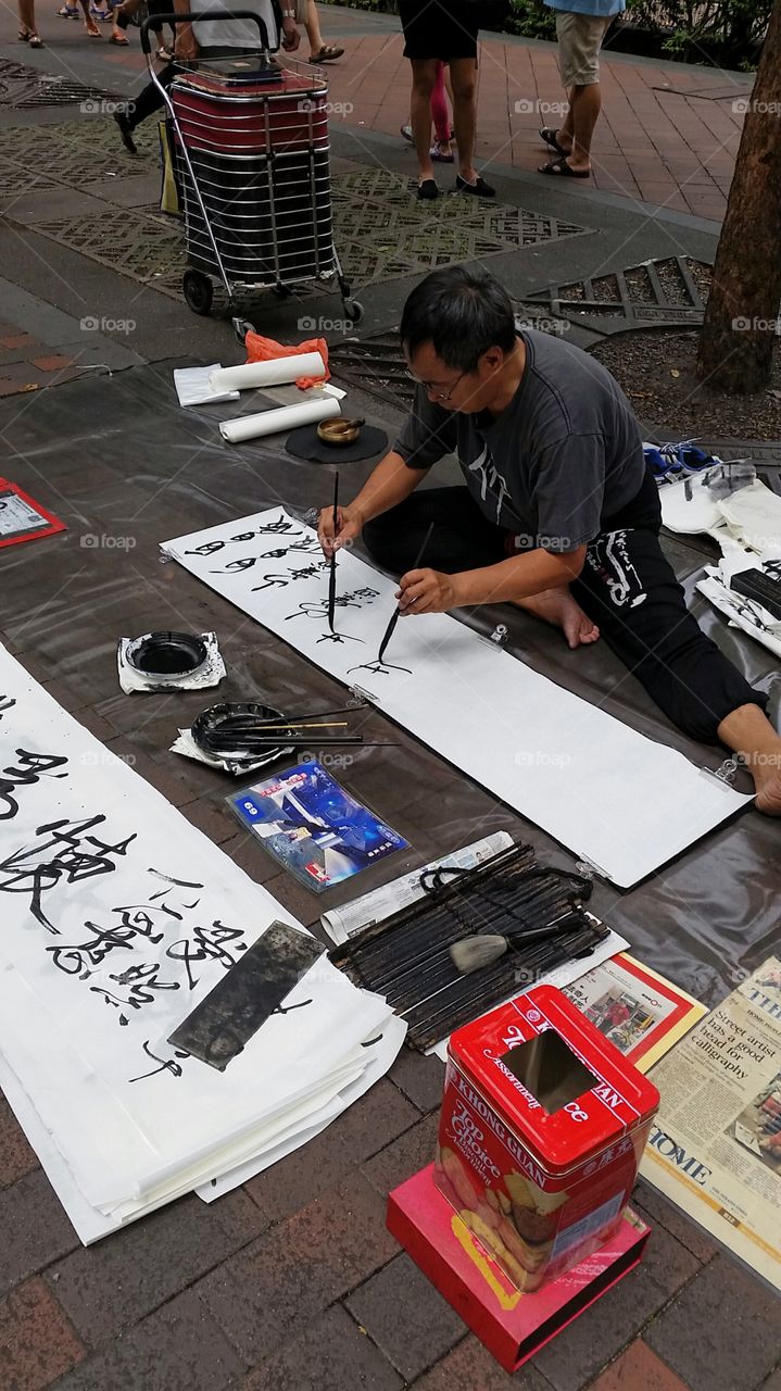 Street artist. Ambidextrous street artist writing Chinese characters in a tourist area in Singapore