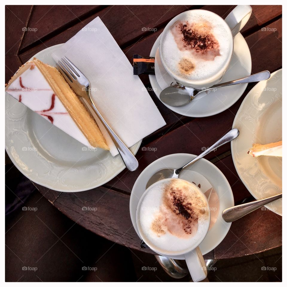 Two cups of cappuccino and lemon cake on a wooden table