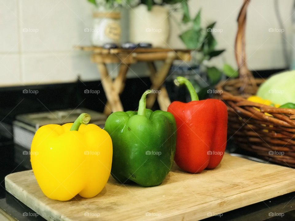 Yellow green red bell pepper on wooden chopping board 