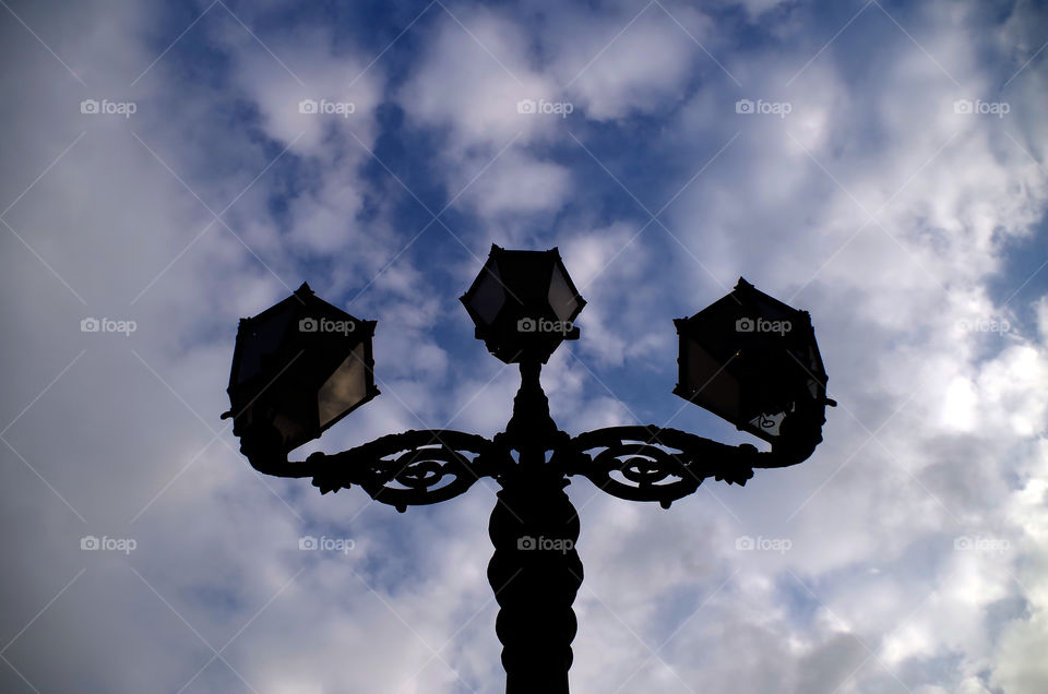 Low angle view of silhouette of gas lantern against cloudy sky in Berlin, Germany.