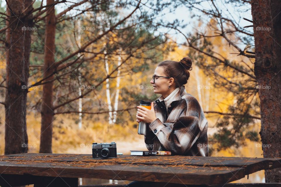 Woman in fall park drinking tea thermos coffee 