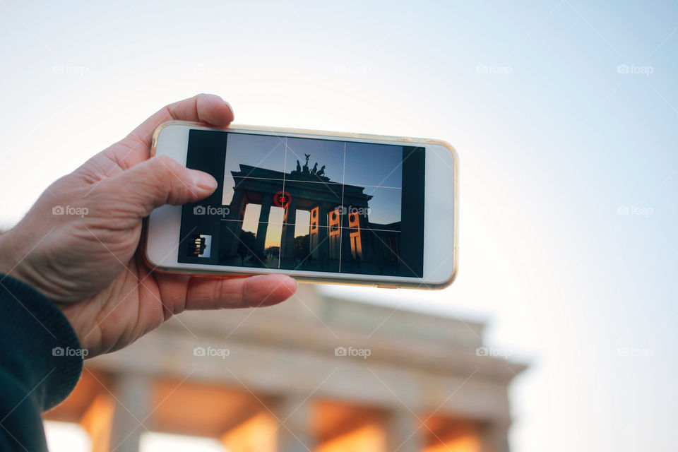 Tourist mobile image in Berlin. Hand with smart phone taking tourist picture of Brandenburger Tor