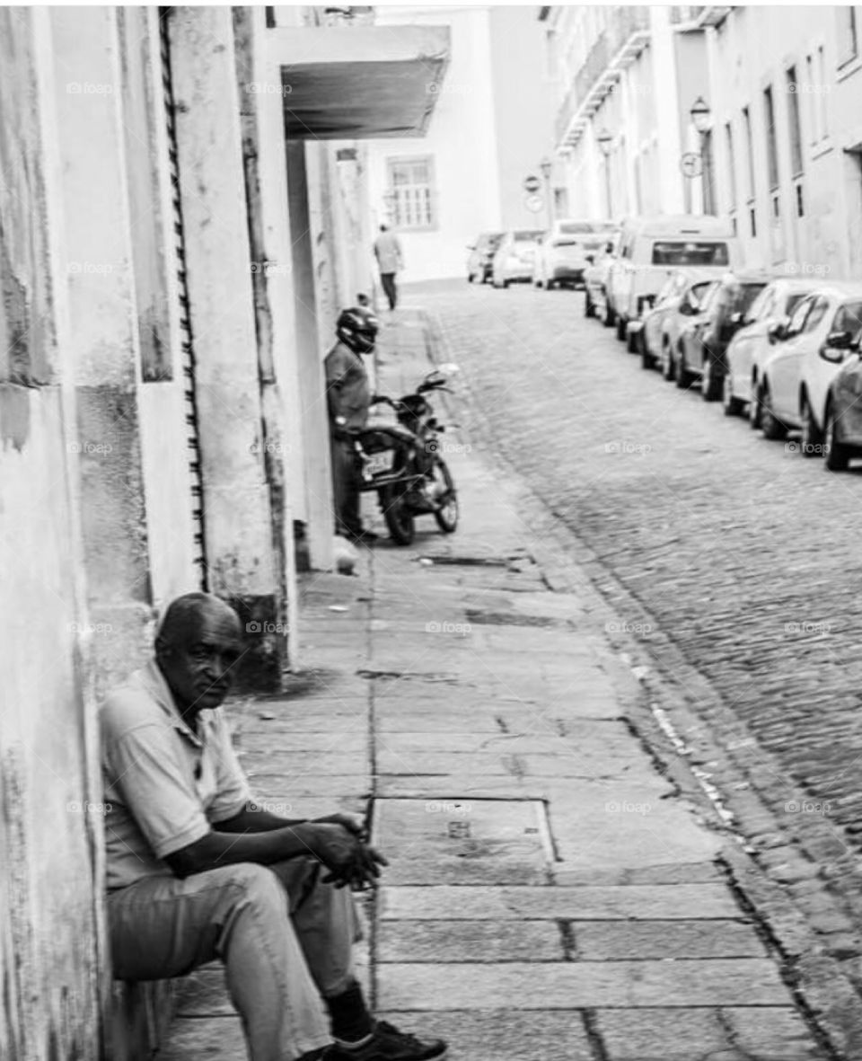 Man sitting near street in city