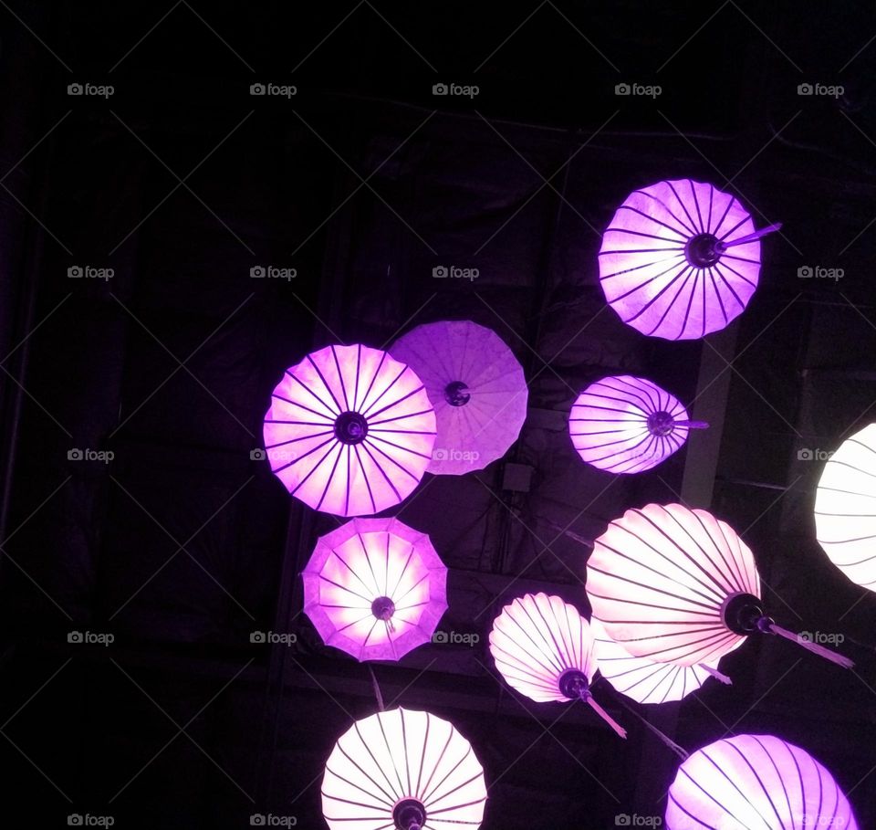 Florescent purple/lavendar colored lamps hang from ceiling in a dark room.