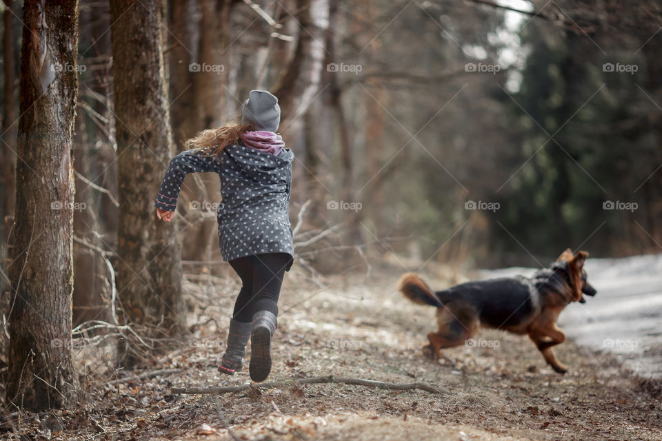 Girl with German shepherd 7-th months old puppy in a spring forest at sunny day