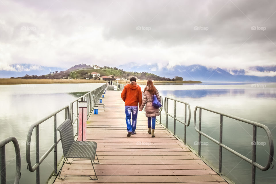 Young Couple In Love Walking Across A Bridge Holding Hands
