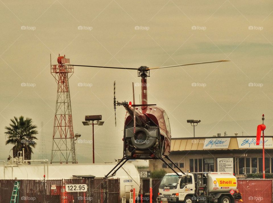 Helicopter Hovering At Airport. Robinson R-22 Helicopter Preparing For Takeoff
