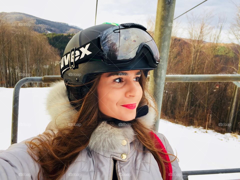 Portrait of young woman wearing Uvex ski glasses and Uvex helmet on the ski lift