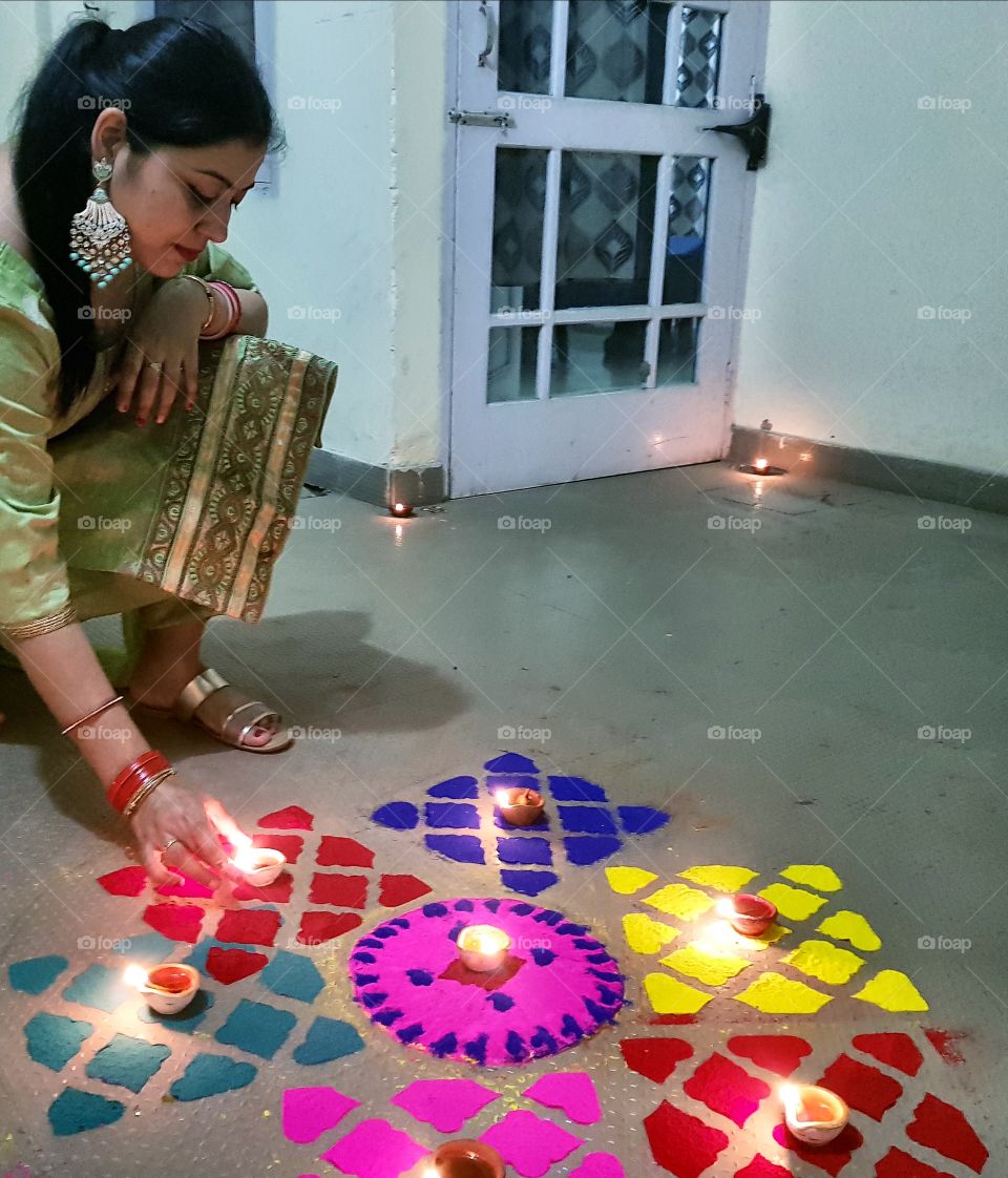 diwali celebration  decorating rangoli with diyas