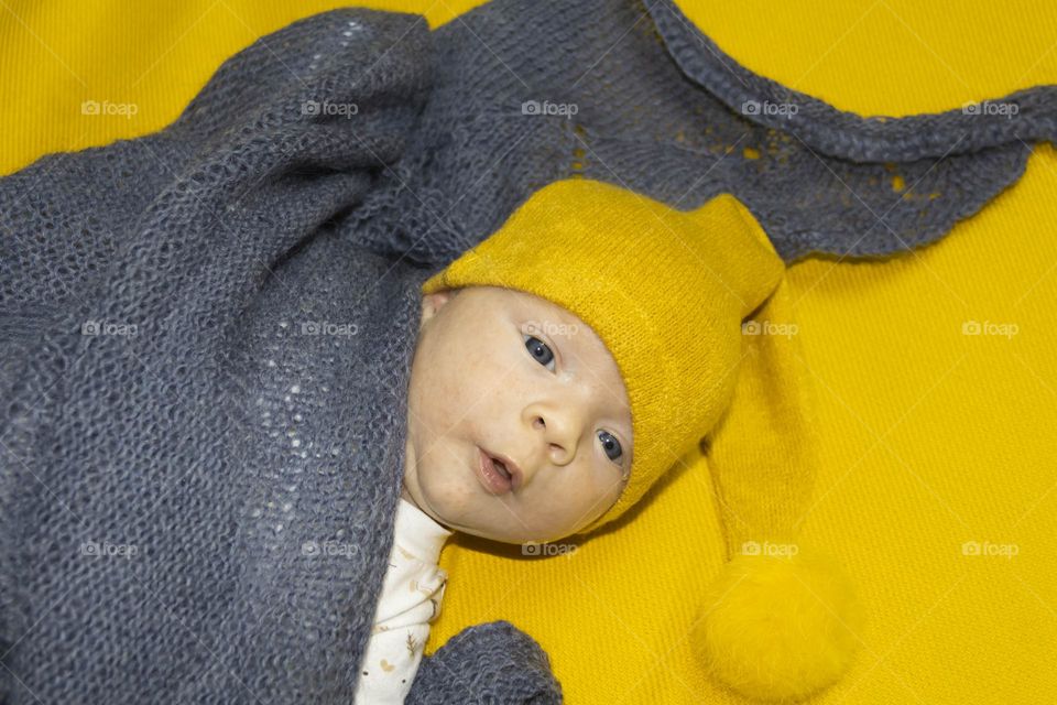 A newborn baby on a yellow and gray background. A photo shoot in the style of Newborn and lifestyle.