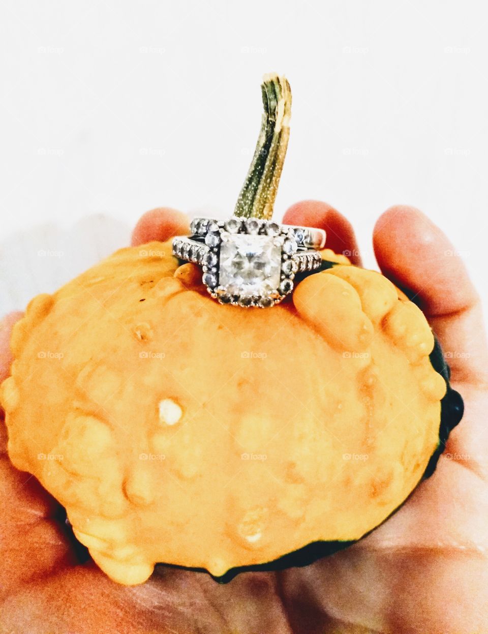 hand holding an orange pumpkin with rings on its stem