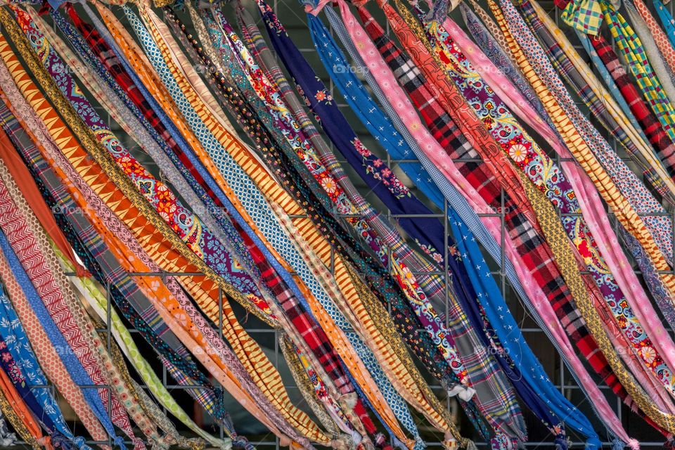 Colorfully designed scarves fabric diagonally intertwined within fence squares