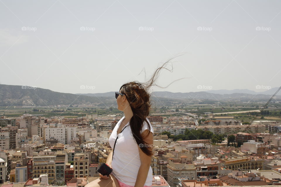 The main object is the model girl. The model is up in a viewpoint. As the background of the photograph you can see the city and the mountains. Taking advantage of the wind I was able to take the photo just when her hair was lifting in the air.