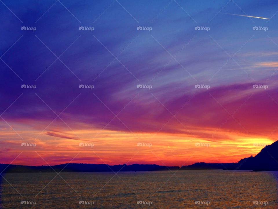 Dramatic sky over silhouetted mountain and sea