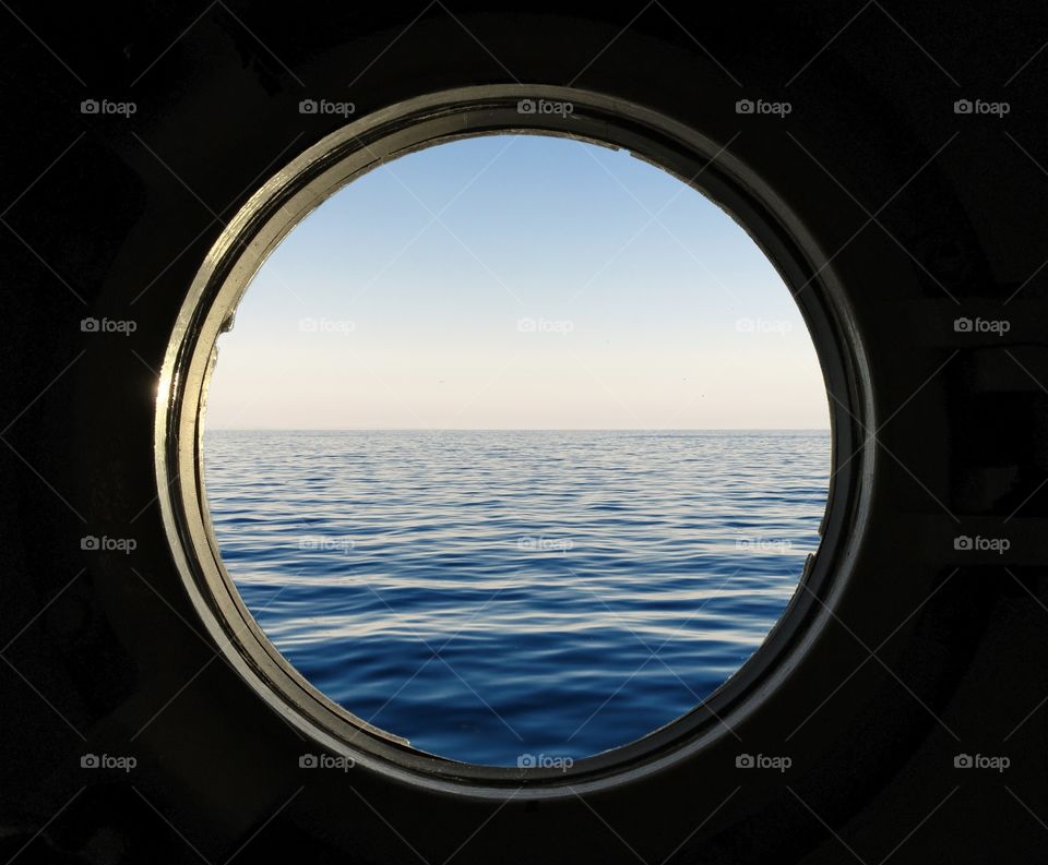 View of sea outside a round window on boat
