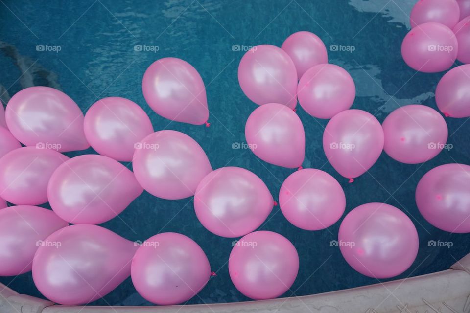 Pink balloons on blue water. Pink rubber balloons floating on a blue water pool