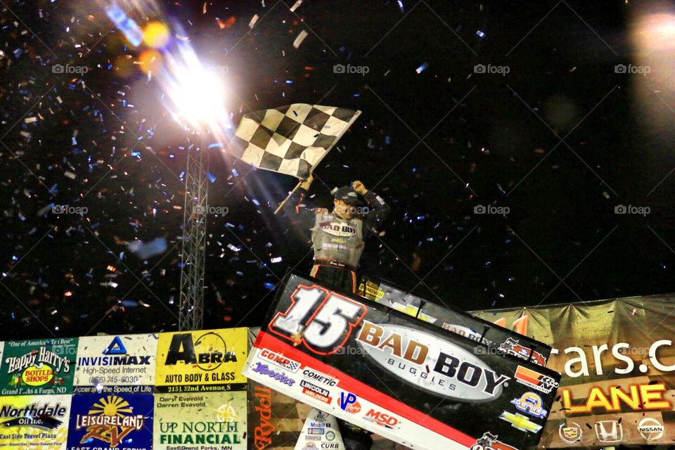 Race Car Driver Waving Checkered Flag in Victory Lane 