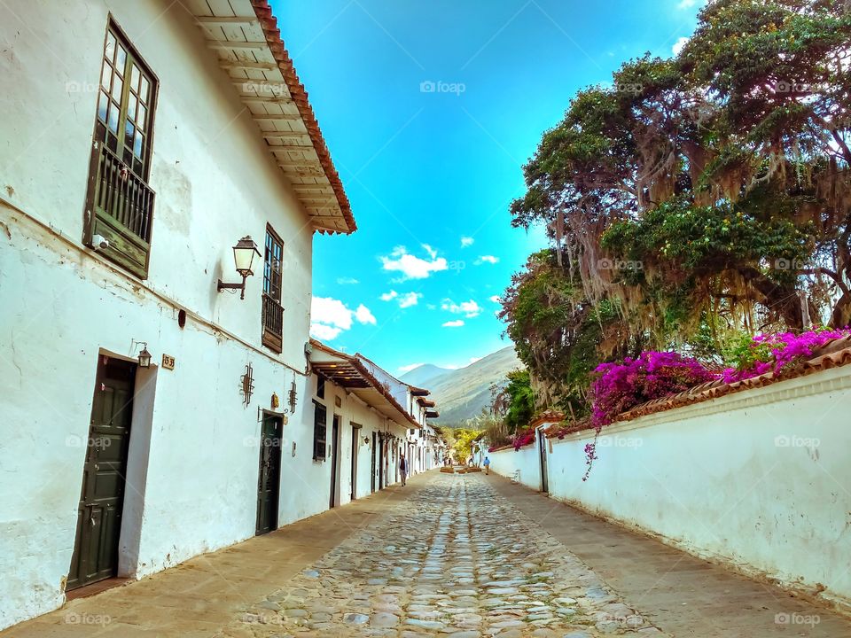 Empty street in Villa de Leyva, on a cloudless blue sky day with the Igüaque mountain in the background. Calle vacía de Villa de Leyva, en día de cielo azul sin nubes con la montaña de Igüaque al fondo. Boyacá, Colombia
