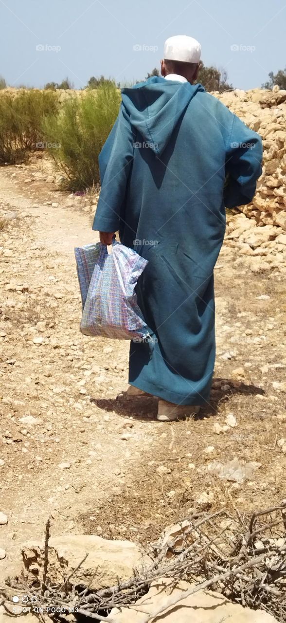 an old man walking in rural road.