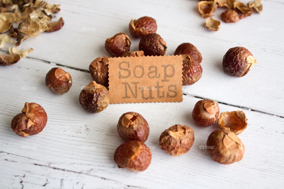 Soap nuts or soap berries on weathered white wooden background with identification placard in natural light