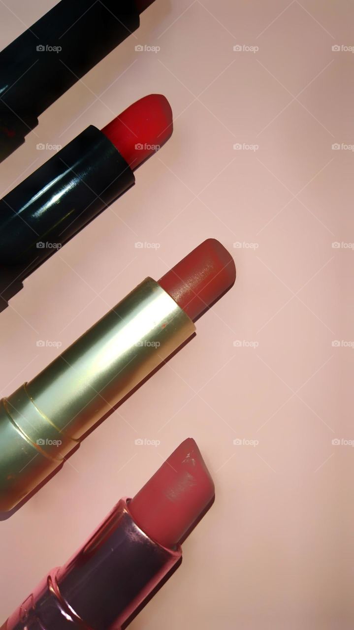 Close view of lipsticks against a pink background.