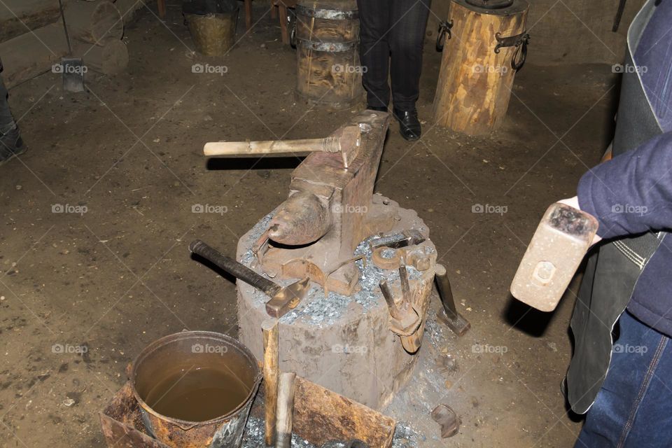 A blacksmith on an anvil makes a horseshoe and metal products from red-hot material.  Blacksmith workshop