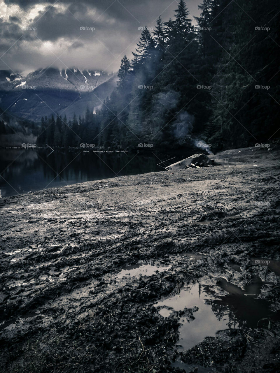 Winter camping in BC. Muddy shore of a lake surrounded by mountains