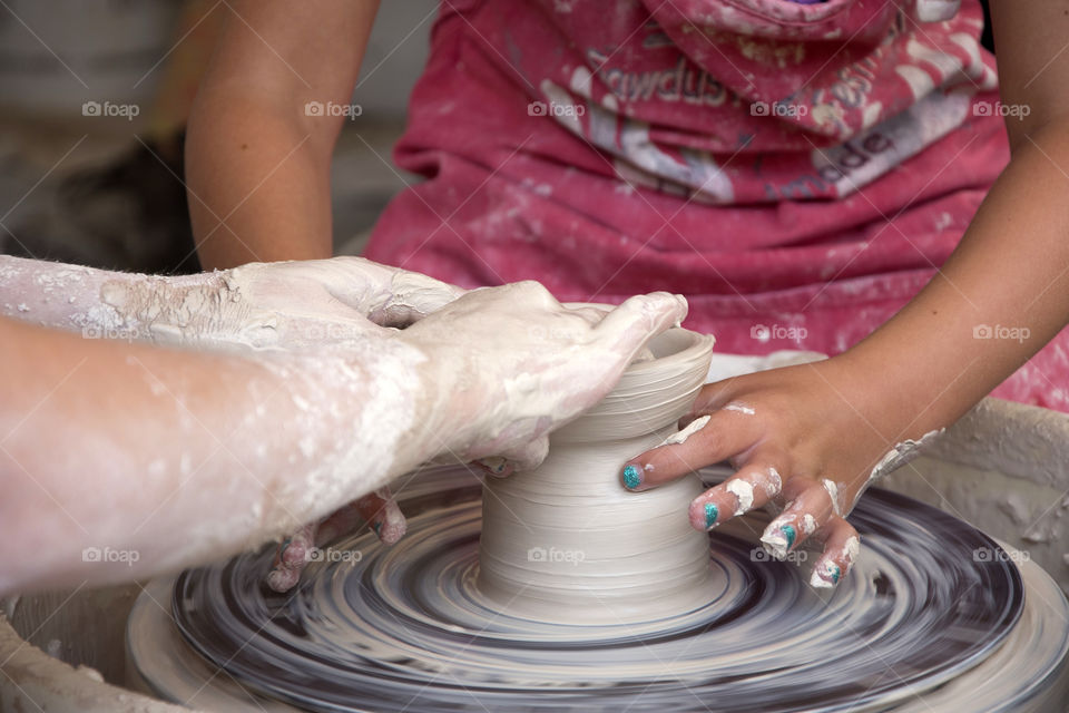 A close up view of hands making a bowl out of clay on a potters wheel!