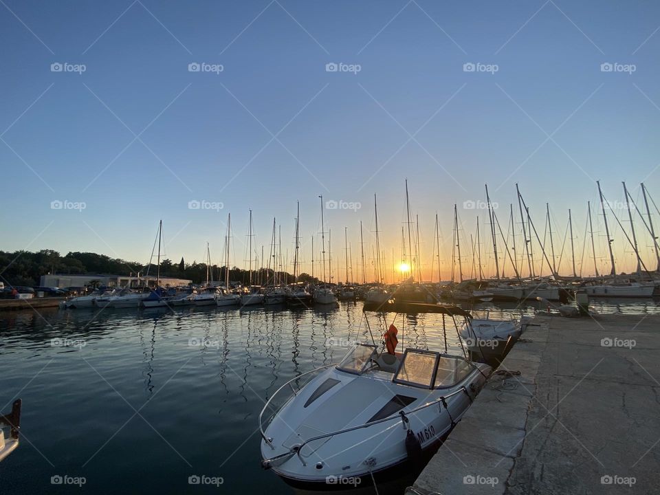 beautiful red summer sunset on the pier against the background of boats, yachts, ships