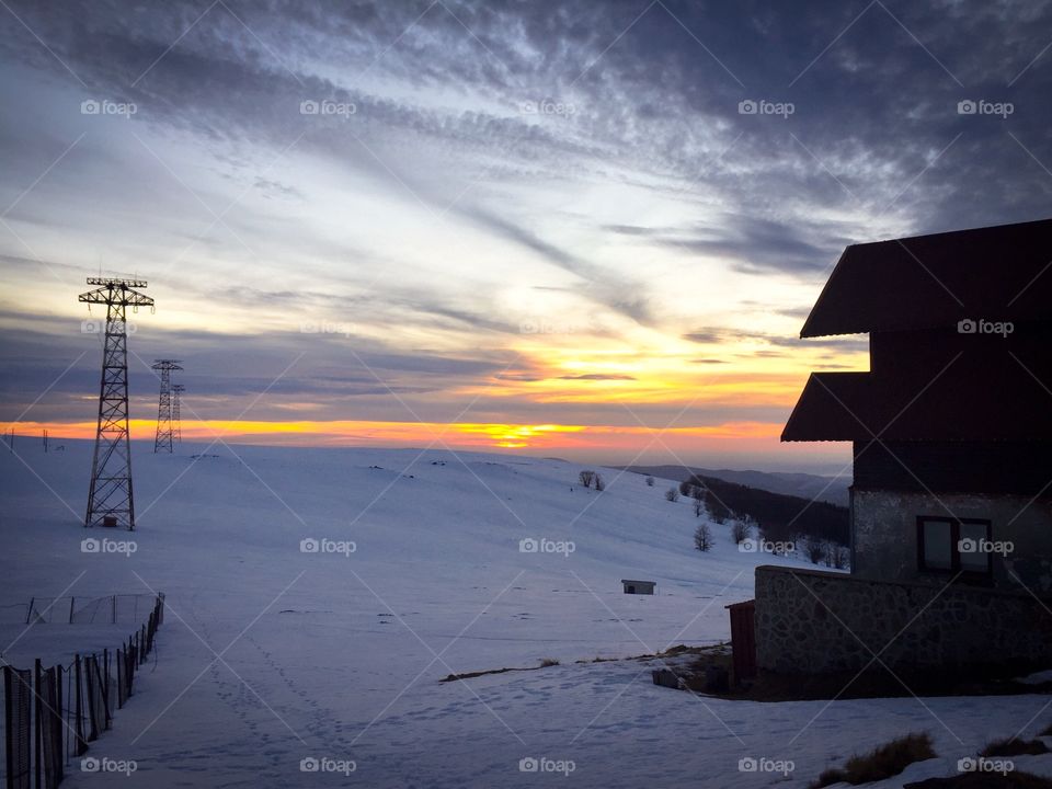 Abandoned house at sunset surrounded by snow