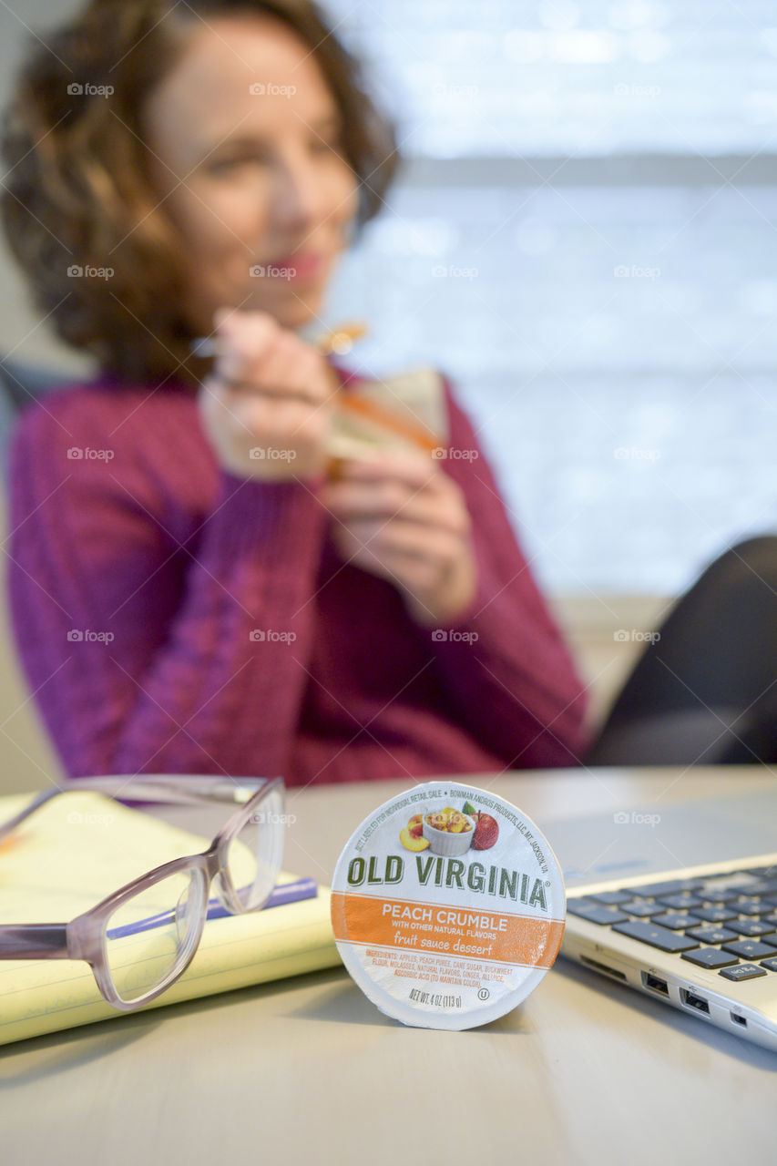 Smiling woman having a snack at her computer 