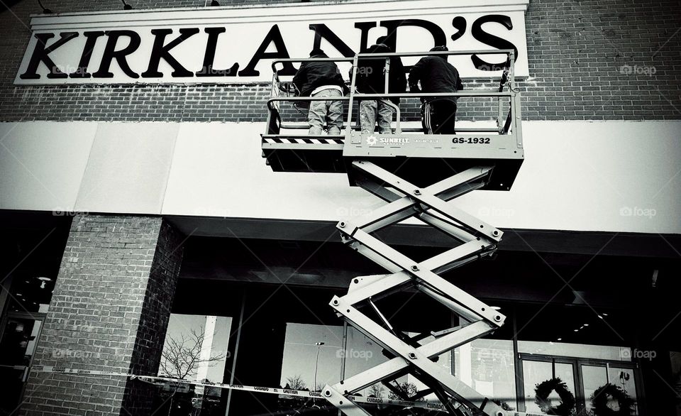 Construction workers fixing a sign for a local store