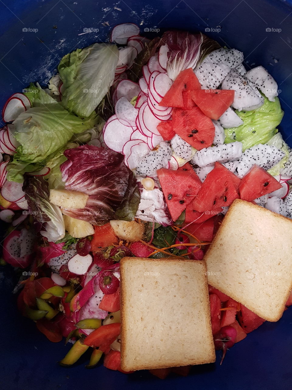Food waste. Overhead close up shot of fresh fruits, vegetables cut and bread in the garbage