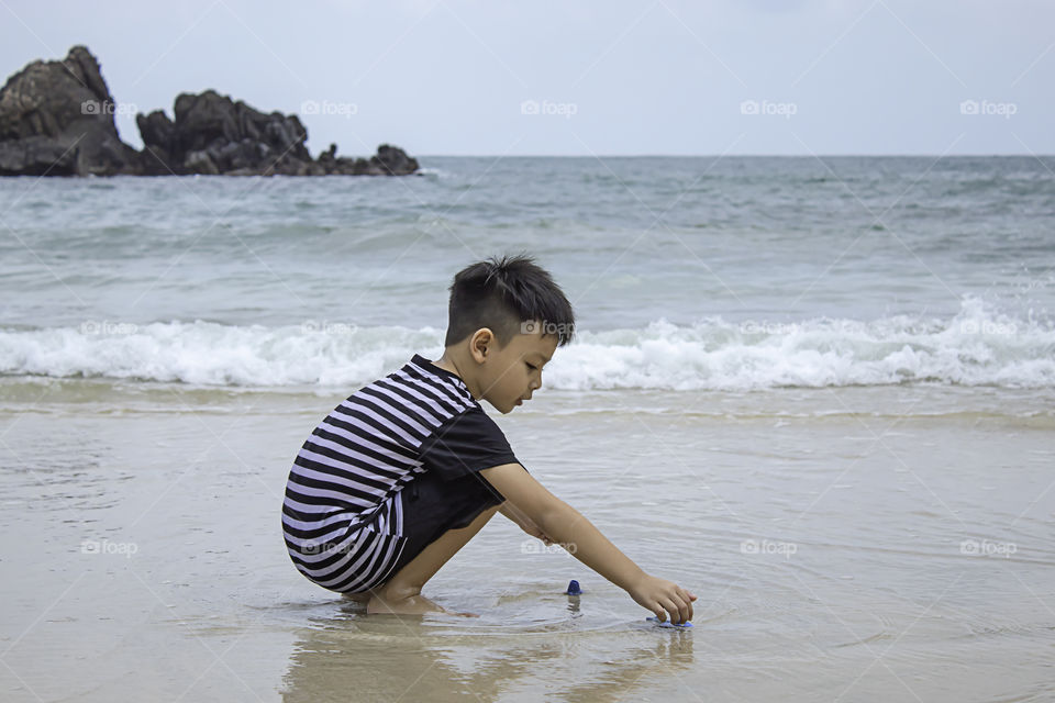 Asian boy playing toy on a sea beach.