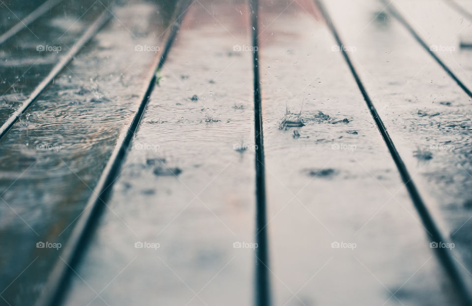 Closeup of wood planks while raining in perspective. Background of wooden natural surface and raindrops