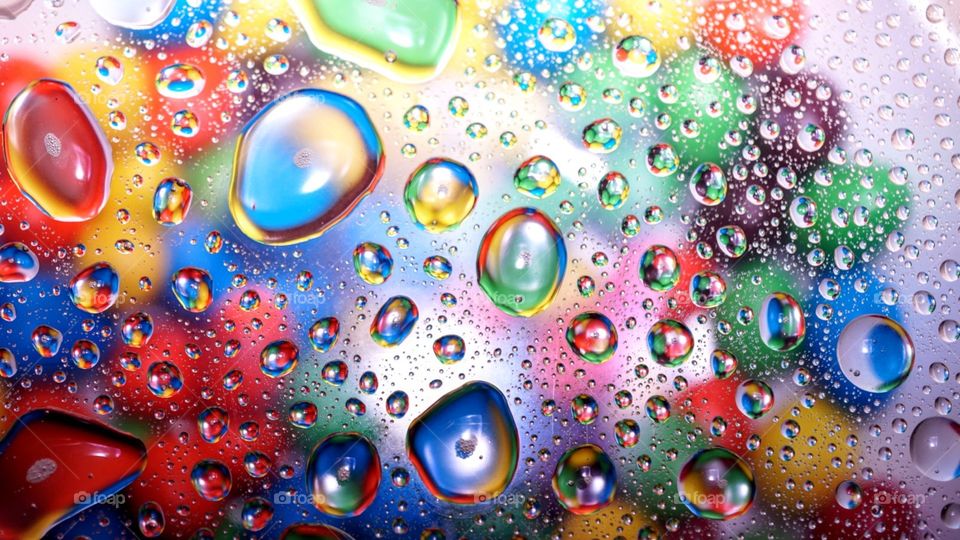 Water droplets illuminated by flash over a colorful candy backdrop.