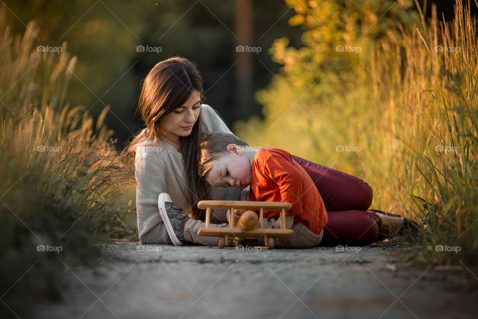 Mother and son with wooden plane at sunset