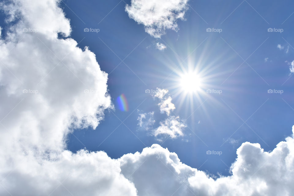 white clouds in blue sky with sun and sunshine