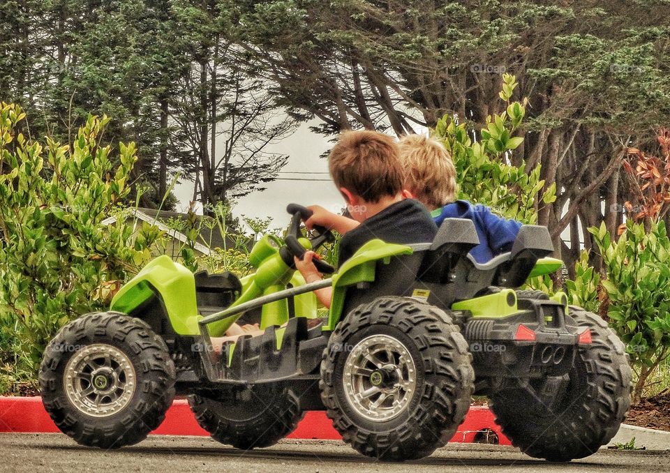 Boys Driving A Toy Car. Young Boys Driving A Miniature Motorized 4x4 Dune Buggy
