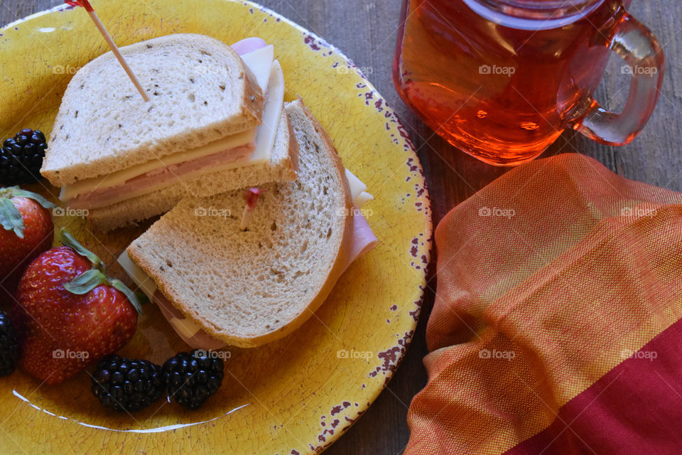 Ham and cheese sandwich with fruit and a glass of juice