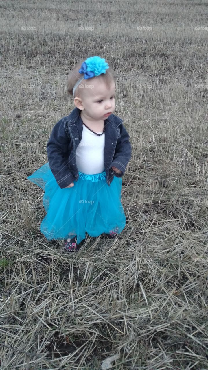 Portrait of a cute girl standing on dry grass