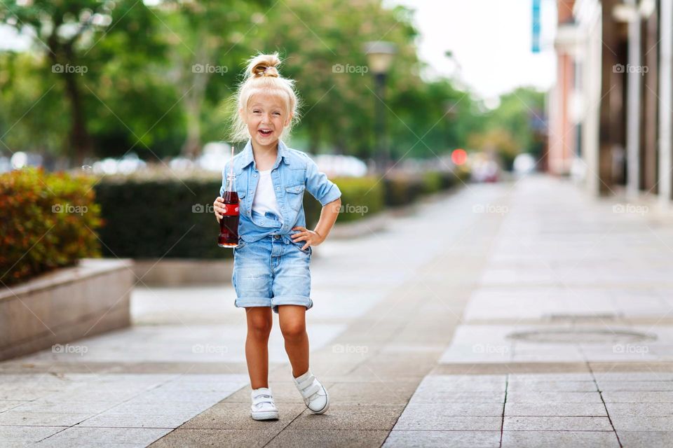 Stylish little Caucasian girl with cold drink