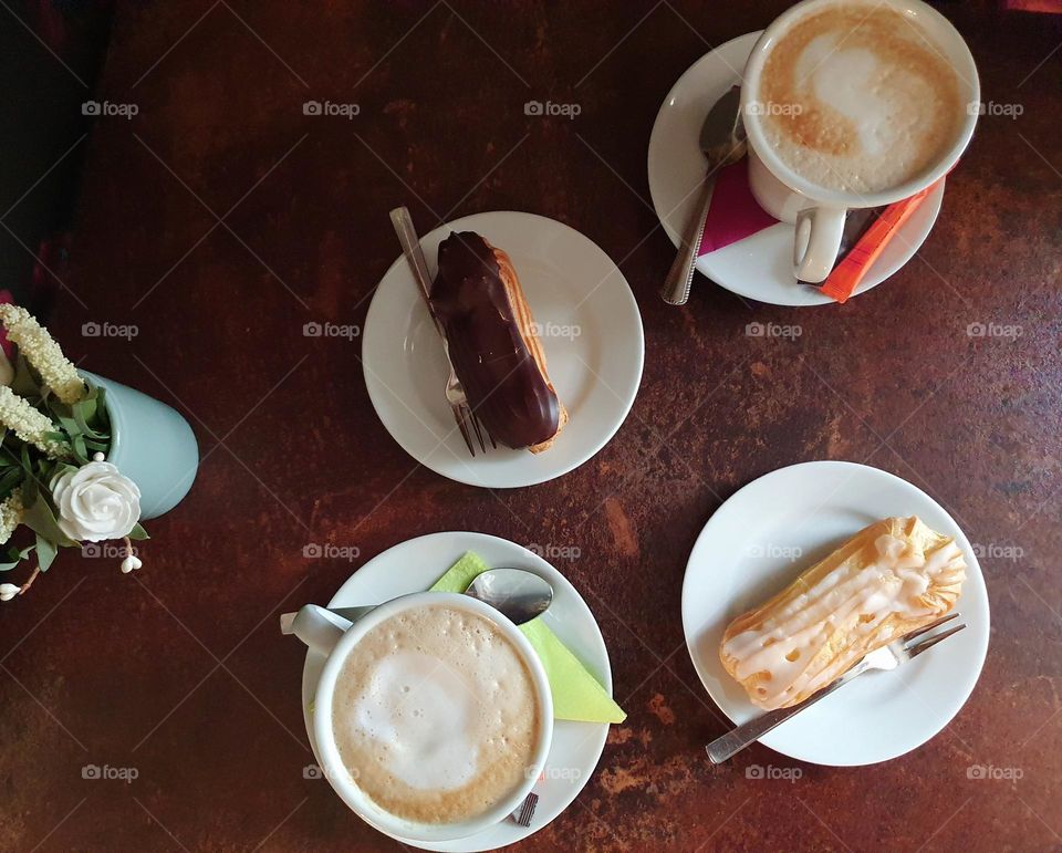 A cup of coffee with eclairs for dessert at lunch