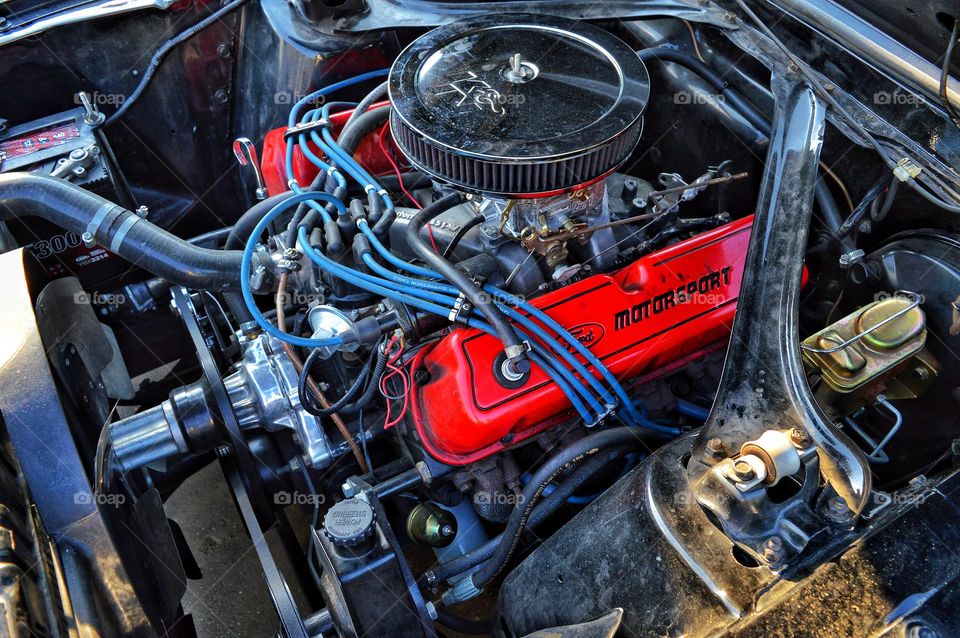 view of the v-shaped engine under the hood of the car. visible chrome air filter old distributor two red valve covers