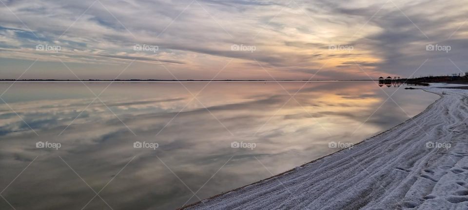 Cloudy sky reflected in Lake Epecuen, Argentina.  Its white coast is thick salt.