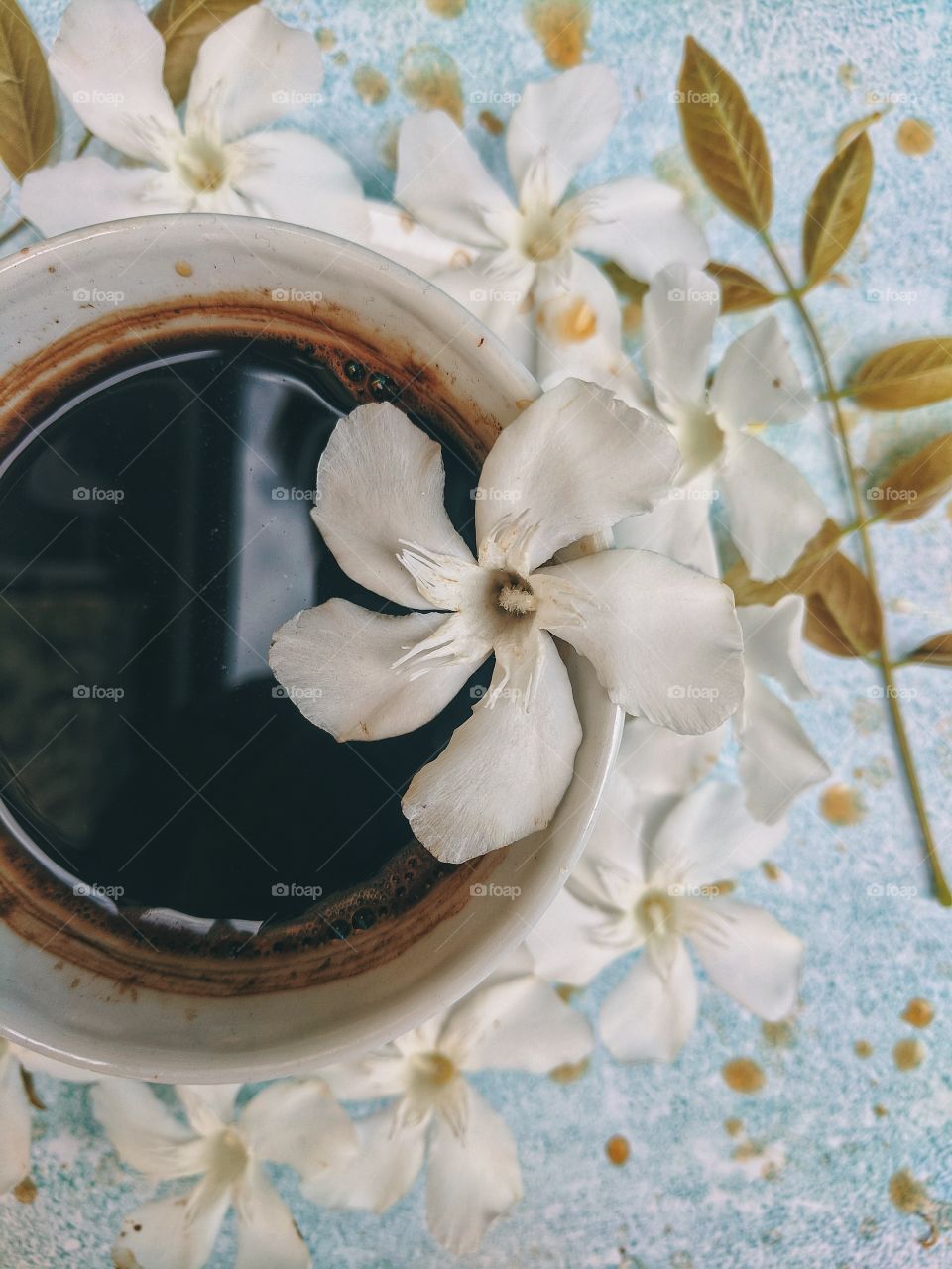 Background of a cup of hot coffee on the table with beautiful flowers close-up. Top view.