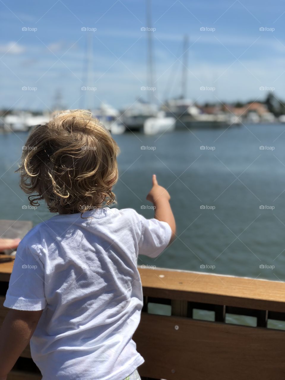 Little boy pointing at boats. 