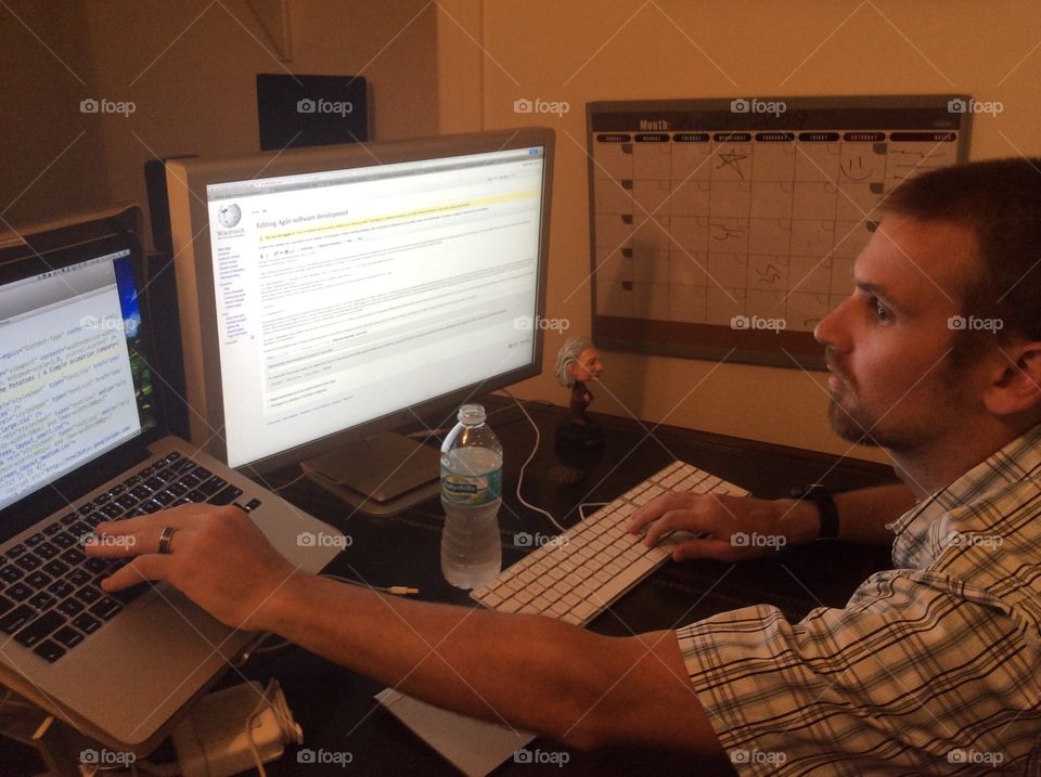 Dual computers. A man working on multiple computers