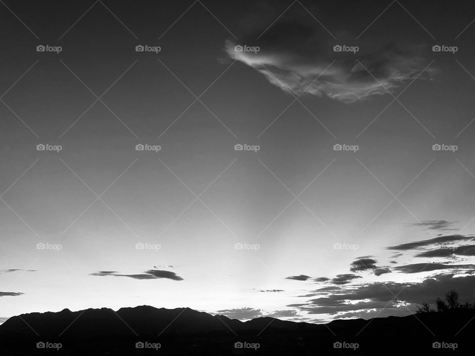 A black and white photo of mountains with clouds above them. 
