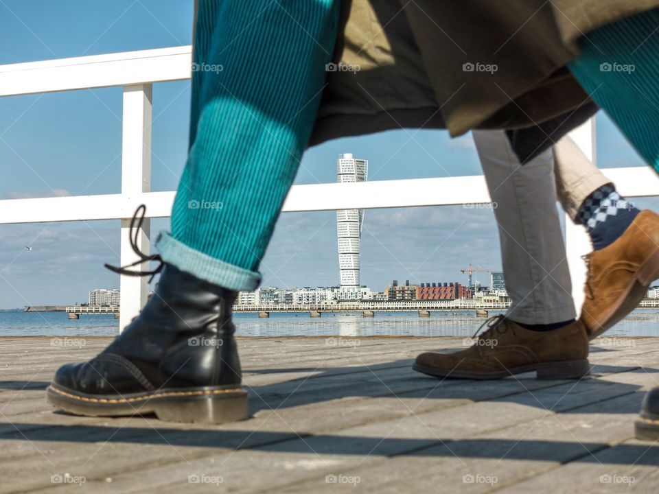 Turning Turso between legs walking on wooden pier with white fence